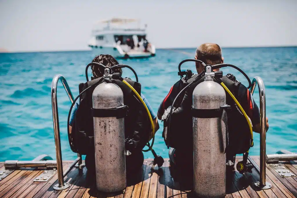 Two scuba divers sitting on a dock in Pensacola Beach, Florida.