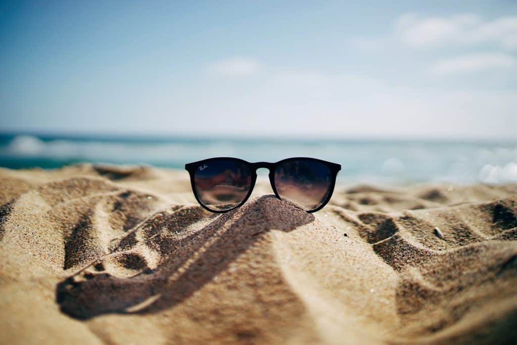 A pair of sunglasses sitting in the sand on the beach.